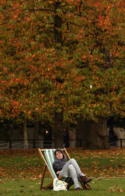 Una mujer se relaja durante la tarde de otoño en el parque de St James, Londres.