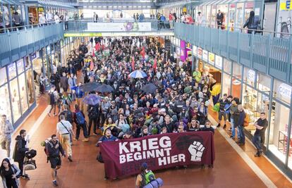 Los pasajeros del tren de protesta 'ZuG20' llevan una pancarta que dice 'Krieg beginnt hier' (cuando empieza la guerra) en la estación central de Hamburgo.