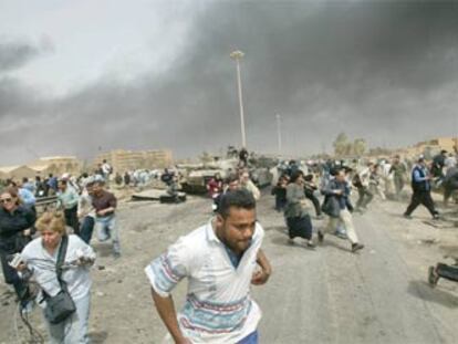 Unos reporteros corren en una calle de Bagdad, el 6 de abril, ante la llegada de aviones.