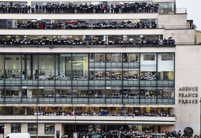 Periodistas de la agencia francesa France-Presse posan durante el minuto de silencio en la fachada de la sede de la agencia.