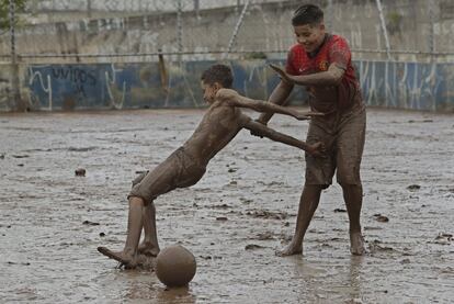 Unos niños juegan al fútbol en un campo cubierto de lodo traído por las lluvias. Se han registrado 76 deslizamientos de tierra y 698 inundaciones en diferentes lugares de la ciudad.