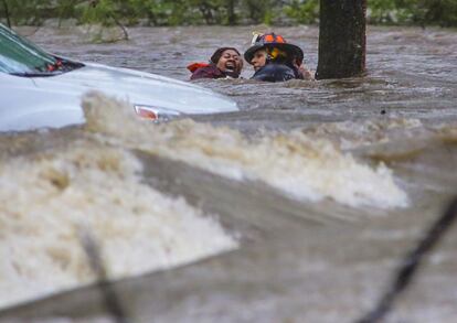 Un bombero evacúa a una mujer de su coche, hundido tras las fuertes lluvias en Little Rock, Arkansas (EE UU).