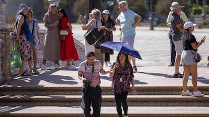 Turistas paseando bajo el sol por Sevilla.