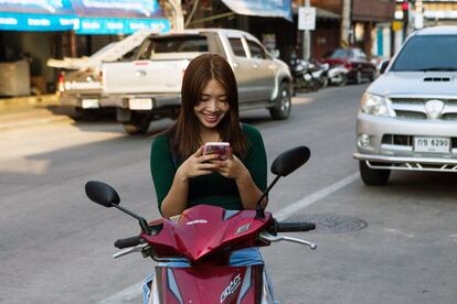 Una mujer utiliza su teléfono móvil sentada en una motocicleta en Nan, Tailandia.