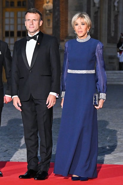 2023, en Versalles. Una cena de gala en honor de Carlos II y Camilla en el templo de Mara Antonieta requera un vestido a la altura y Brigitte Macron lo resolvi con este vestido largo azul noche rematado en su cuello, cintura y mangas por tiras de cristales Swarovski plateados. 