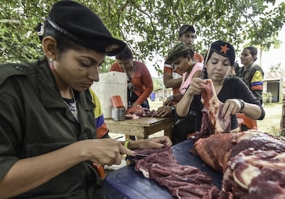 Members of the Revolutionary Armed Forces of Colombia (FARC) prepare meat at a camp in the Colombian mountains on February 18, 2016. Many of these women are willing to be reunited with the children they gave birth and then left under protection of relatives or farmers, whenever the imminent peace agreement puts an end to the country's internal conflict. AFP PHOTO / LUIS ACOSTA