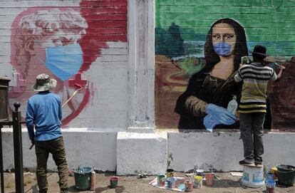 Artistas callejeros realizan murales en los que reproducen obras famosas con mascarillas para concienciar sobre la prevención frente al coronavirus, en Bombay (India).