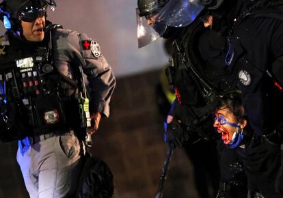 Una manifestante herida es detenida durante una protesta por la violencia racial en Portland (EE UU). La ciudad norteamericana mantiene sus protestas cada noche, 100 días después de la muerte del afroestadounidense George Floyd a manos de un policía blanco.