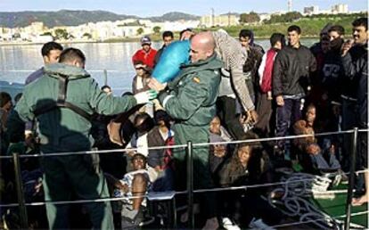 Guardias civiles ayudan a una inmigrante embarazada a salir de la patrullera que la rescató de una patera.