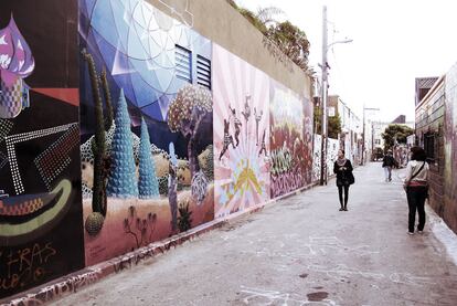 Los murales del Clarion Alley se han convertido en reclamo de turistas y curiosos que deambulan por Mission District. En la imagen, dos paseantes contemplan los trabajos <i>Hearts of Gold, Fists of Fury</i> (dcha.) de Oasis for Girls y <i>Lo llevas dentro</i> de Jet Martinez (izqda.), quien recreó dentro de la silueta central del mural la vista que el espectador tiene del propio callejón desde ese punto: Clarion Alley dentro de Clarion Alley.