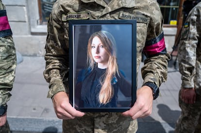 A soldier holds a photograph of writer Victoria Amelina during her funeral at the Church of St. Peter and Paul in Kyiv, July 5, 2023.