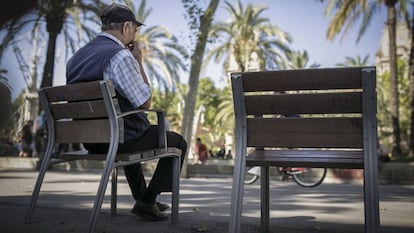 Un señor mayor descansa en un banco en la calle, en Barcelona.