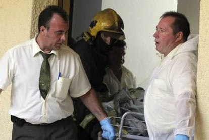 Miembros del servicio funerario sacan el cadáver de uno de los fallecidos en el incendio