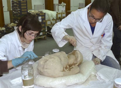 Dos arqueólogas limpian la escultura hallada en las excavaciones de Bilbilis