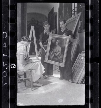 Una mujer trabaja en el inventario de una de las pinturas de la colección Las Descalzas Reales junto a dos soldados republicanos.  Octubre de 1936, Madrid.