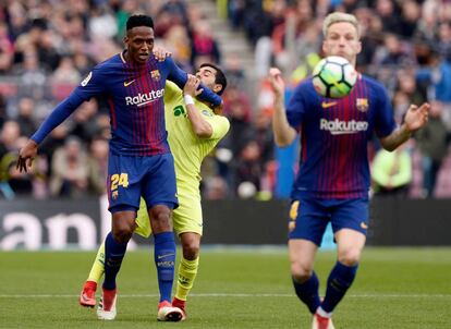 Yerry Mina y Ángel se enfrentan mientras Ivan Rakitic controla la pelota.