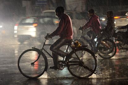 Un viandante indio monta en bicicleta durante las fuertes lluvias en Jalandha.