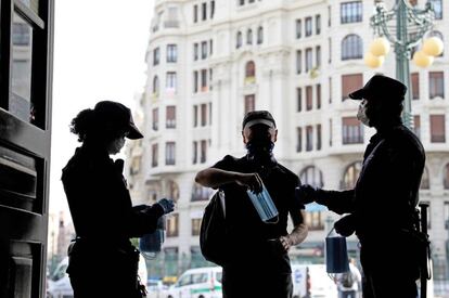 Un policía reparte mascarillas en la estación de Renfe de Valencia.