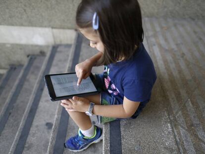 Una ni&ntilde;a lee un libro digital en una tableta. 