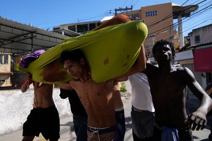 Hombres de Complexo do Alemão cargan un cuerpo envuelto en una sábana, luego de que el operativo policial resultara en múltiples heridos. El portavoz de la Policía, Ivan Blaz, ha informado de que entre las víctimas hay una mujer de 50 años, un policía militar y “16 criminales”, tal y como ha informado ‘O Globo’.