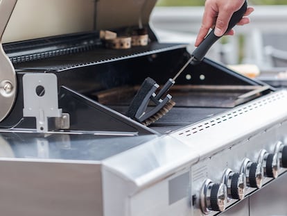 Una persona pasando el cepillo por la barbacoa.
