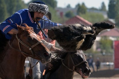 Un jinete ruso (azul) y uno chino montan sus caballos mientras participan en el deporte tradicional de Asia Central llamado Buzkashi, Kok-Boru o Oglak Tartis, durante los World Nomad Games, en el lago Issyk Kul de Cholpon-Ata (Kirguistán).