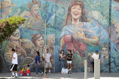 Habitantes del barrio hispano de Los Ángeles (California) caminan frente a un mural sobre la cultura mexicana, en una fotografía de archivo.
