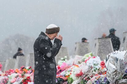 Un albanés de Kosovo reza frente a la tumba de un pariente mientras sus familiares y amigos conmemoran el decimonoveno aniversario de la masacre de Racak.