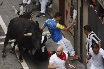 Uno de los toros de la ganadería de Fuente Ymbro engancha a un joven su paso por la calle Estafeta.