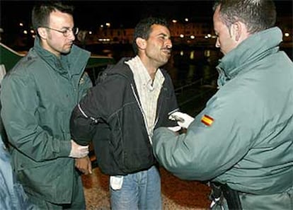 Miembros de la Guardia Civil trasladan a uno de los 32 inmigrantes detenidos en la costa este de Fuerteventura.