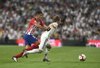 Rodrigo, del Atlético de Madrid, y Modric luchan por el esférico.