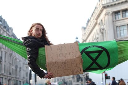 Desde el pasado lunes, el grupo lleva a cabo varios actos de protesta en céntricos enclaves con las que han bloqueado carreteras y obligado a desviar rutas de transporte público. En la foto, un activista se despierta el cuarto día de protesta ambiental en una hamaca en el ajeteadro distrito comercial del centro de Londres, Oxford Circus.