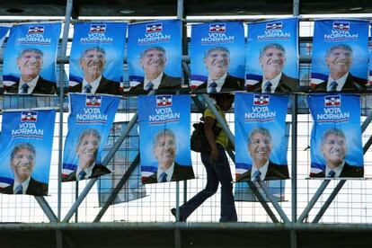 Mulher cruza uma ponte com propagada do candidato do Arena.