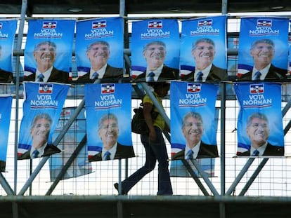 Mulher cruza uma ponte com propagada do candidato do Arena.