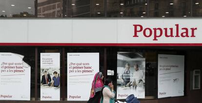 Unas mujeres pasan ante una oficina del Banco Popular en el Paseo de Gracia esquina con la calle Aragón de Barcelona.