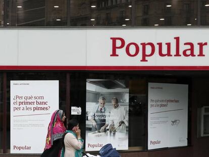 Unas mujeres pasan ante una oficina del Banco Popular en el Paseo de Gracia esquina con la calle Aragón de Barcelona.