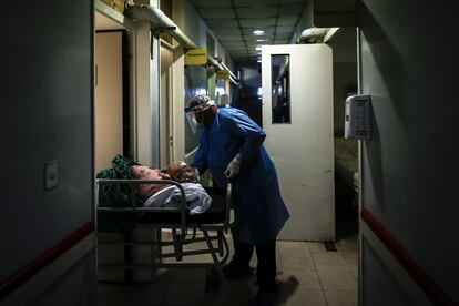 Un camillero realiza el traslado de una mujer con covid-19 en una unidad de terapia intensiva, en Buenos Aires.