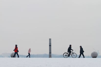 Personas pasean por una calle nevada, en Harbin (China).
