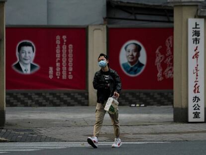Un hombre con una máscara camina frente a los retratos del presidente chino Xi Jinping y el difunto presidente Mao Zedong, el pasado 10 de febrero en Shanghai.