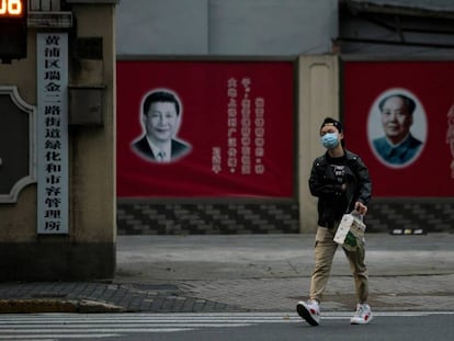 Un hombre con una máscara camina frente a los retratos del presidente chino Xi Jinping y el difunto presidente Mao Zedong, el pasado 10 de febrero en Shanghai.