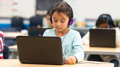 Un grupo de niños usa recursos informáticos en clase.