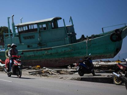 Supervivientes del terremoto en Indonesia pasan frente a un barco desplazado en mitad de una calle, en Palu.