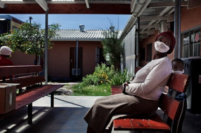 Una mujer y su hijo, en la sala de espera al aire libre de la clínica de diagnóstico y tratamiento de la tuberculosis Mayenzeke, ubicada en el asentamiento urbano de Khayelitsha, cerca de Ciudad del Cabo (Sudáfrica).