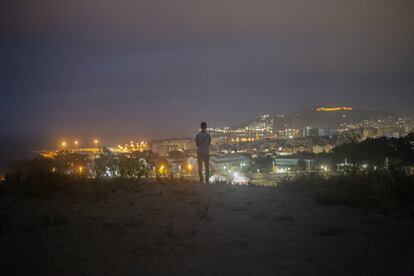 Un adolescente observa las luces de la ciudad desde el campamento del Cortijo con el mar de fondo