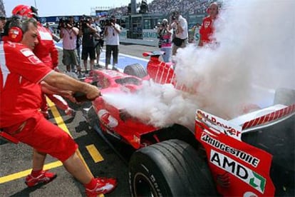 Un mecánico trata de apagar el fuego en el coche de Schumacher.