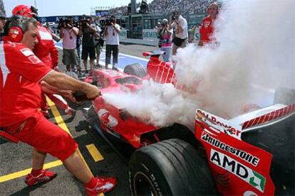 Un mecánico trata de apagar el fuego en el coche de Schumacher.