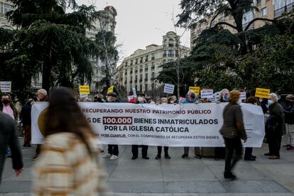 Varias personas con una pancarta en la que se lee: 'Más de 100.000 bienes inmatriculados por la Iglesia católica', participan en una concentración a las puertas del Congreso de los Diputados para manifestar su disconformidad con el acuerdo alcanzado por Gobierno e Iglesia sobre las inmatriculaciones de los bienes de esta última,