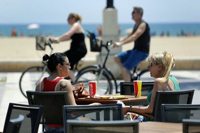 Dos jóvenes se refrescan en una terraza junto a la playa de la Malvarrosa de Valencia.