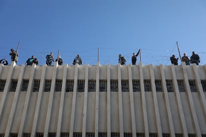 Varios hombres de pie junto a un muro de la prisión de Saidnaya.