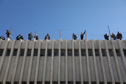 Varios hombres de pie junto a un muro de la prisión de Saidnaya. 